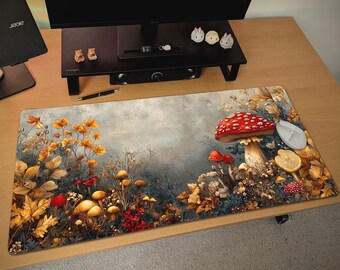 May include: A rectangular mouse pad featuring a whimsical forest scene with mushrooms, autumn leaves, and flowers in shades of red, yellow, and brown. A white computer mouse is on the right side of the pad.