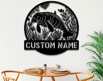 May include: Black metal wall art featuring a manatee swimming in a circle of coral and seaweed. The art includes the text "CUSTOM NAME" at the bottom.