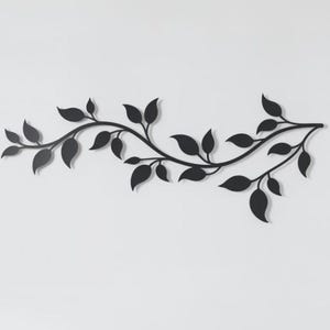Könnte beinhalten: Ein schwarzes Metall-Wanddekor mit einer stilisierten Weinrebe mit Blättern. Die Blätter sind in einem einfachen, eleganten Design gehalten, und das Stück ist an einer weißen Wand befestigt. Dieses dekorative Element fügt eine Note von naturnaher Dekoration hinzu.