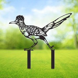 May include: Black metal silhouette of a roadrunner bird perched on two metal stakes. The bird is facing left and has a long tail. The stakes are black and are about 30 cm tall.