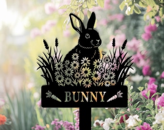 May include: Black metal garden stake featuring a bunny silhouette amidst flowers and grass. The word "BUNNY" is displayed on a sign with carrot accents. Ideal for outdoor garden decor.
