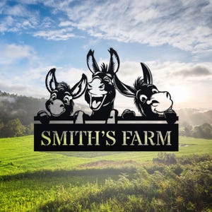 Puede incluir: Un letrero de metal negro con tres burros de dibujos animados asomándose por la parte superior. El letrero dice "SMITH'S FARM".
