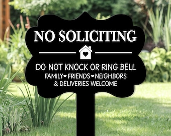 May include: Black garden sign with white text reading "NO SOLICITING". It also states "DO NOT KNOCK OR RING BELL. FAMILY, FRIENDS, NEIGHBOURS & DELIVERIES WELCOME." A house icon is centered above the second line.