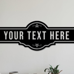 Puede incluir: Letrero de pared en blanco y negro con el texto "YOUR TEXT HERE". El letrero tiene un borde decorativo y adornos. Una pieza moderna para la decoración del hogar.
