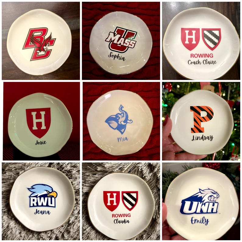 Puede incluir: Nueve platos de cer&aacute;mica blanquecina con bordes dorados, cada uno con un logotipo o inicial universitario diferente. Algunos platos tienen nombres debajo de los logotipos. Los logotipos incluyen un &aacute;guila roja, un elefante azul y una P con rayas de tigre.