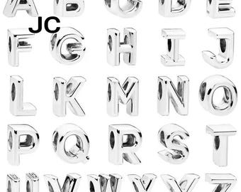 May include: A collection of silver alphabet charms, each designed as a letter from A to Z. The charms are shiny and have a hole for stringing. The letters are in a sans-serif font. The letters "JC" are also visible.