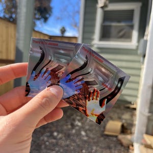 May include: Two square stickers featuring a surreal hallway scene with a patterned floor and dark curved walls. Each sticker displays the text "There is no escape" in red, with one sticker also showing the text "Wake up" and a glowing hand graphic.