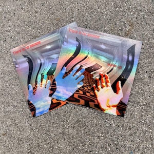 May include: Two square holographic stickers featuring a surreal hallway with a geometric orange and black carpet pattern. Each sticker displays a hand in the foreground, the text "There is no escape" at the top, and "Wake up" on the right side.