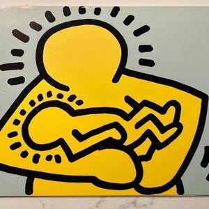 Peut inclure: Une œuvre d'art de style Keith Haring représentant une figure jaune enlacant une autre plus petite, sur fond bleu clair. Les contours noirs et les détails en pointillés et lignes rayonnantes sont caractéristiques. Impression sur une surface rectangulaire.