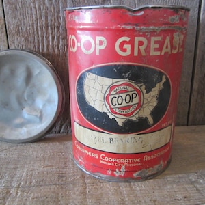 K&ouml;nnte beinhalten: Vintage rote und wei&szlig;e CO-OP-Fettb&uuml;chse mit Deckel. Die Dose tr&auml;gt den Text "O-OP GREASE" und ein Etikett mit einer Karte der Vereinigten Staaten und den Worten "National CO-OP Cooperatives". Das Etikett lautet auch "BRL BEARING".