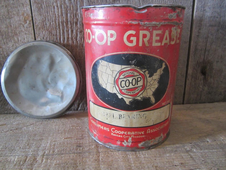 K&ouml;nnte beinhalten: Vintage rote und wei&szlig;e CO-OP-Fettb&uuml;chse mit Deckel. Die Dose tr&auml;gt den Text "O-OP GREASE" und ein Etikett mit einer Karte der Vereinigten Staaten und den Worten "National CO-OP Cooperatives". Das Etikett lautet auch "BRL BEARING".