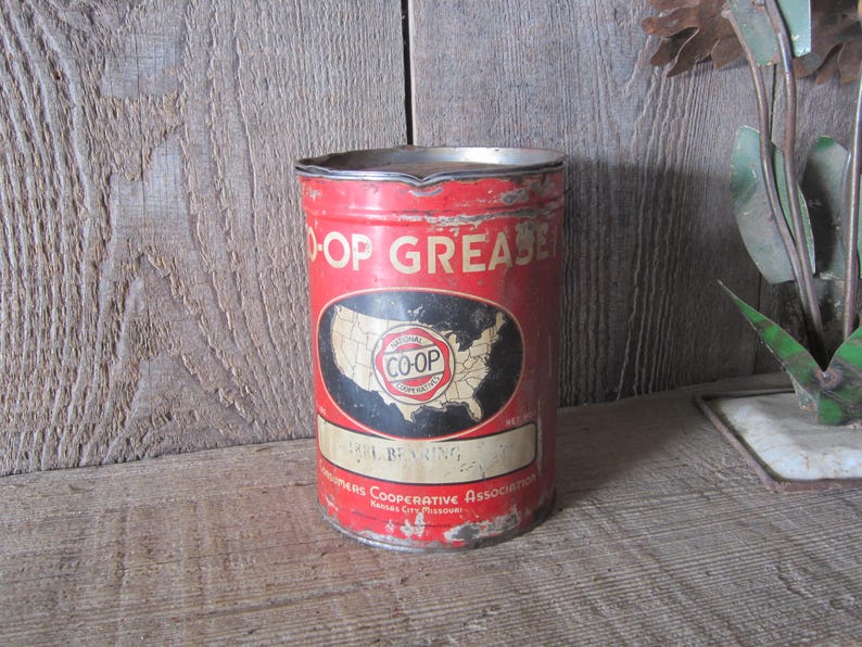 K&ouml;nnte beinhalten: Vintage rote und wei&szlig;e Coop Grease Dose mit einer Karte der Vereinigten Staaten. Auf der Dose steht "Co-op Grease". Die Dose ist leicht verrostet, was ihr ein rustikales Aussehen verleiht.