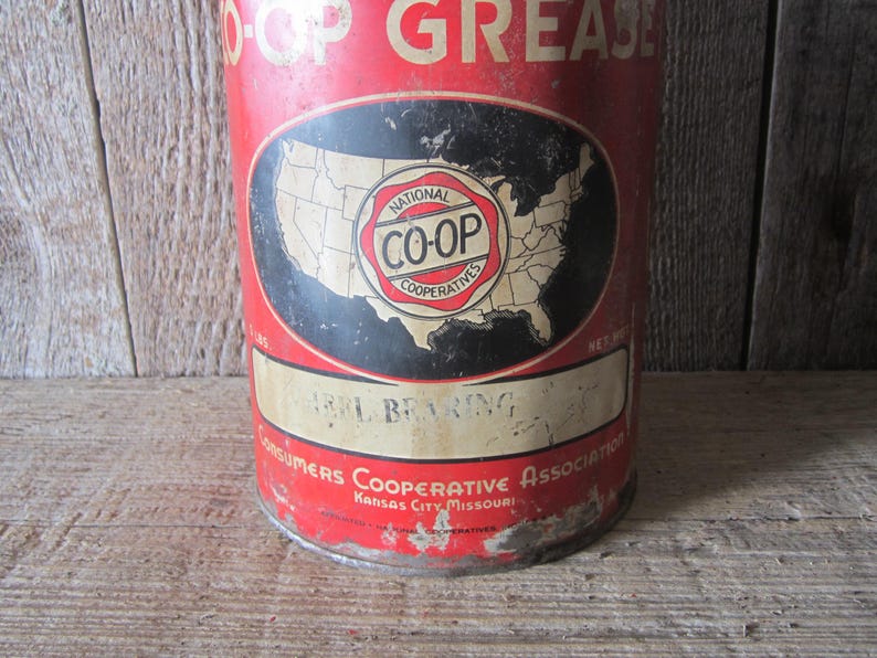 K&ouml;nnte beinhalten: Vintage rote und wei&szlig;e Metall-Dose mit CO-OP-Fett. Die Dose hat ein schwarzes Oval mit einer Karte der Vereinigten Staaten und dem CO-OP-Logo. Die Dose tr&auml;gt auch die Aufschrift "Heavy Bearing" und "Consumers Cooperative Association Kansas City Missouri."