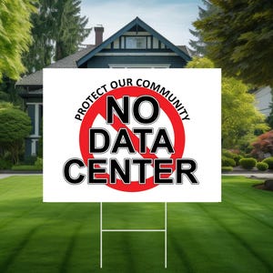 May include: A white yard sign with the text "NO DATA CENTER" inside a red circle with a line through it. The sign also says "PROTECT OUR COMMUNITY". The sign is in a yard with a house in the background.