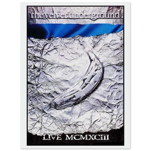 May include: A poster with a silver banana on a textured background. The text "the velvet underground" is at the top, with a blue stripe beneath it. The words "LIVE MCMXCIII" are at the bottom.