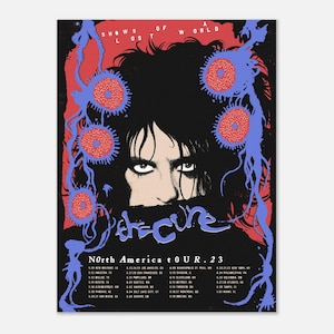 May include: A poster advertising The Cure's North America tour in 2023. The design features a portrait with black hair and eyes, framed by red and blue abstract shapes. The band's name and tour dates are printed on the poster.