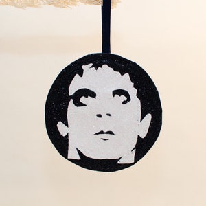 Könnte beinhalten: Schwarzer und weißer Glitzer-Weihnachtsbaumschmuck mit der Silhouette eines Gesichts.