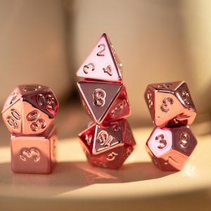 Juego de dados poliédricos de resina de metal rosa con hojas reales y bordes afilados para juegos de D&D, RPG y MTG.