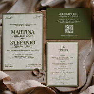 Olive green and cream wedding stationery cards with two silver rings rest on folded draped fabric.
