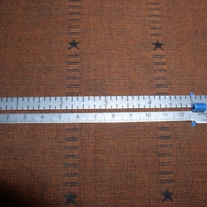 May include: A silver sewing and knitting gauge with blue end caps. The gauge is marked with inches from 1 to 12. The text on the gauge reads "Sewing & Knit Ting Gauge Made in China."