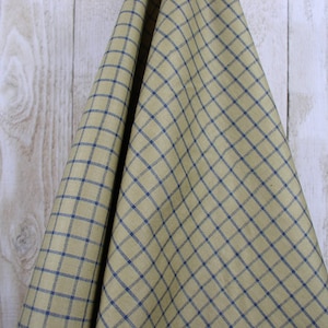 May include: A close-up of a fabric with a yellow and blue checkered pattern. The fabric is folded in half and draped over a wooden surface.