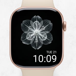 May include: A rose gold smartwatch with a black screen displaying a white floral design. The time is 10:09 AM, and the date is Tuesday, the 21st. The watch has a cream-colored band.