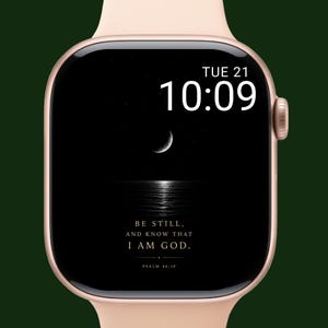 Op de afbeelding: Een roségouden smartwatch met een zwart scherm met een halve maan, sterren en de tekst "BE STILL, AND KNOW THAT I AM GOD. PSALM 46:10." De tijd is 10:09 uur op dinsdag de 21e.
