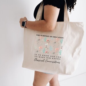May include: A beige tote bag with a floral design and the text "THE PURPOSE OF EDUCATION IS TO KNOW GOD AND TO MAKE HIM KNOWN Classical Conversations".