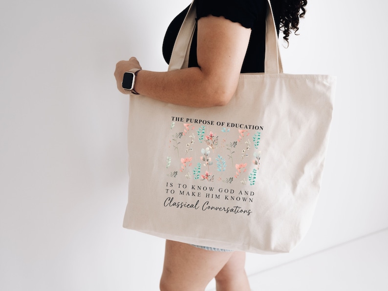 May include: A beige tote bag with a floral design and the text "THE PURPOSE OF EDUCATION IS TO KNOW GOD AND TO MAKE HIM KNOWN Classical Conversations".