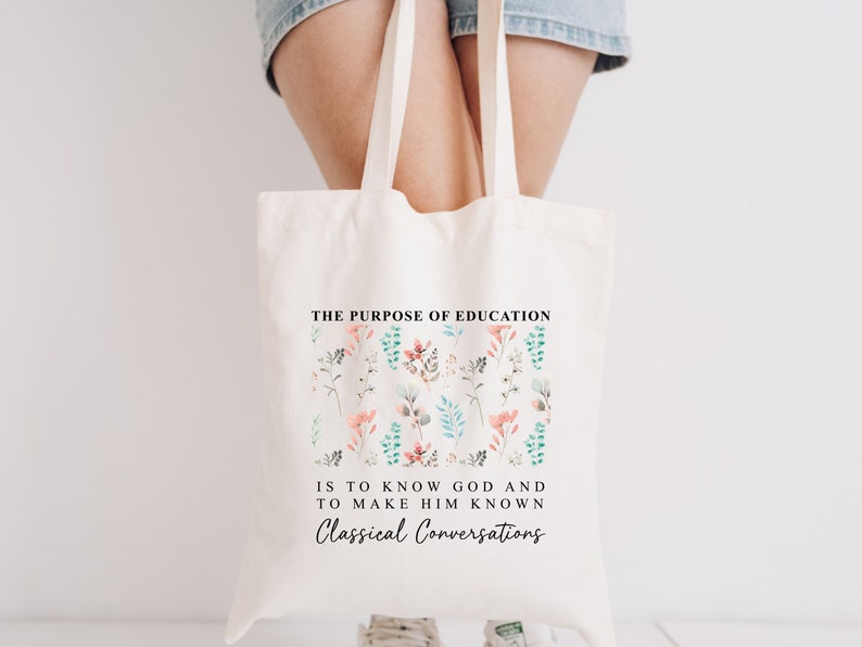 May include: A white tote bag with a floral design and the text "THE PURPOSE OF EDUCATION IS TO KNOW GOD AND TO MAKE HIM KNOWN Classical Conversations".