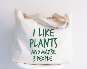 May include: A white canvas tote bag with green text that reads "I like plants and maybe 3 people."