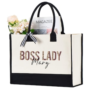May include: A white canvas tote bag with black trim and handles. The bag has a black and brown leopard print design with the text "Boss Lady Mary" printed on the front.