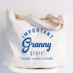 May include: A white canvas tote bag with blue text that reads "Important Granny Stuff* *mainly snacks actually"