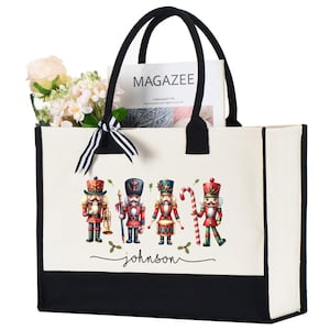 May include: A canvas tote bag with black handles and a black bottom panel. The bag features a festive design of four nutcracker soldiers. The name "johnson" is printed below the nutcrackers. The bag is filled with flowers and a magazine.