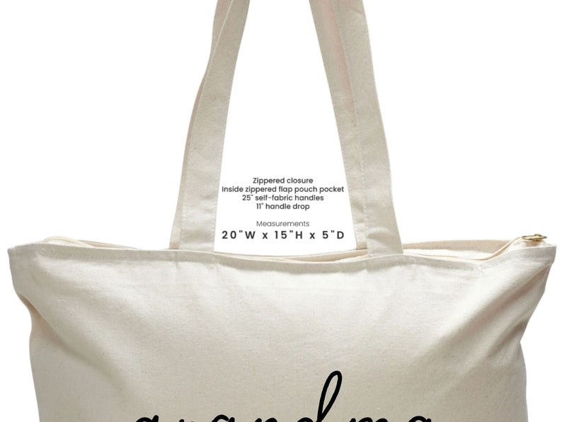 Op de afbeelding: Een cr&egrave;mekleurige canvas tote bag met zwarte tekst die "Ritsluiting, Binnenzak met ritsklep, 25" zelfstof handvatten, 11" handvatval, Metingen, 20"B x 15"H x 5"D" luidt.