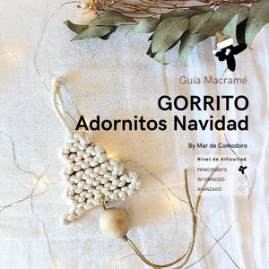 Puede incluir: Un adorno de árbol de Navidad de macramé blanco con una cuenta de madera y un cordón dorado. El adorno está sobre un fondo de tela blanca con una cadena de luces blancas. El texto "GORRITO Adornitos Navidad" está escrito en negro en la parte superior de la imagen. El texto "By Mar de Comodoro" está escrito en negro debajo del adorno. El texto "Nivel de dificultad" está escrito en negro debajo del texto "By Mar de Comodoro". Los textos "PRINCIPIANTE", "INTERMEDIO" y "AVANZADO" están escritos en negro debajo del texto "Nivel de dificultad".
