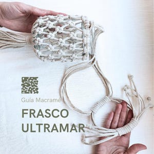 Puede incluir: Un macramé blanco para colgar plantas con un frasco de vidrio. El macramé está hecho con cordón de algodón grueso y tiene un borla en la parte superior. El texto "Guia Macrame FRASCO ULTRAMAR" está impreso sobre un fondo blanco.