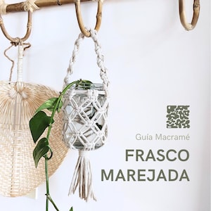 Puede incluir: Un macetero de macramé blanco con un frasco de vidrio en su interior. El macetero está colgado de una repisa de madera. El texto "Guia Macrame FRASCO MAREJADA" es visible en la imagen.