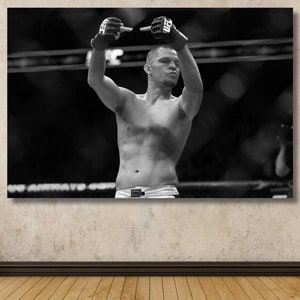 Può includere: Foto in bianco e nero di un uomo in un ring di boxe che alza le braccia in segno di vittoria. È a torso nudo e indossa i guantoni da boxe.