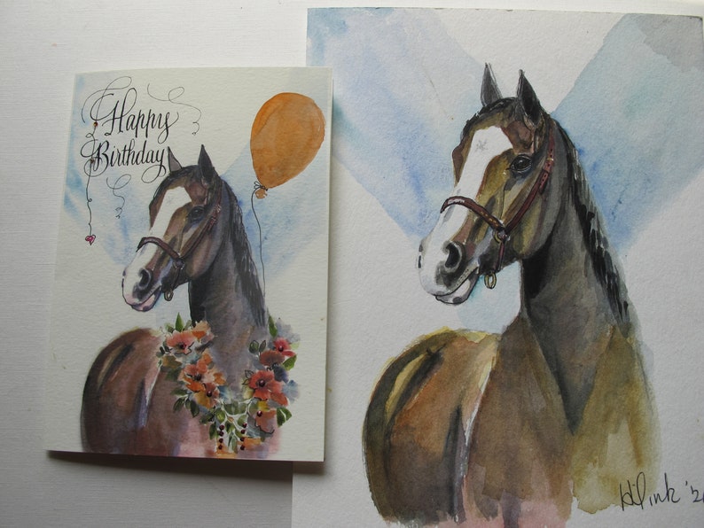 May include: A watercolor painting of a brown horse with a white blaze on its face. The horse is wearing a brown halter and has a floral garland around its neck. The painting is on a white background with a blue sky in the background. The painting says "Happy Birthday" in cursive.