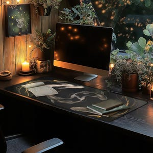 K&ouml;nnte beinhalten: Eine schwarze Schreibtischmatte mit einem goldenen und wei&szlig;en abstrakten Design. Die Matte liegt auf einem schwarzen Schreibtisch mit einem Computermonitor, einem Notizbuch und ein paar anderen Gegenst&auml;nden.