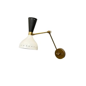 May include: A black and white wall sconce with a brass arm and a round base. The sconce has a white shade with holes and a black top.