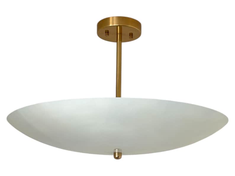 May include: A modern ceiling light fixture with a white, oval-shaped shade. The fixture has a gold-colored stem and a circular ceiling mount. The light is suspended from the ceiling, providing ambient illumination.