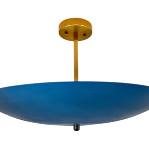 May include: A modern ceiling light fixture with a blue, bowl-shaped shade. The fixture has a gold-colored stem and ceiling mount. The shade is a deep blue color. The light fixture is designed to be mounted on a ceiling.