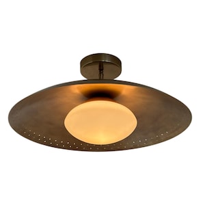 May include: A brass ceiling light fixture with a round, frosted glass shade and a perforated metal shade.