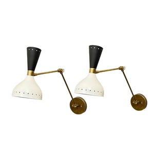 May include: A pair of black and white wall sconces with brass arms. The sconces have a white, perforated shade and a black, cone-shaped top.