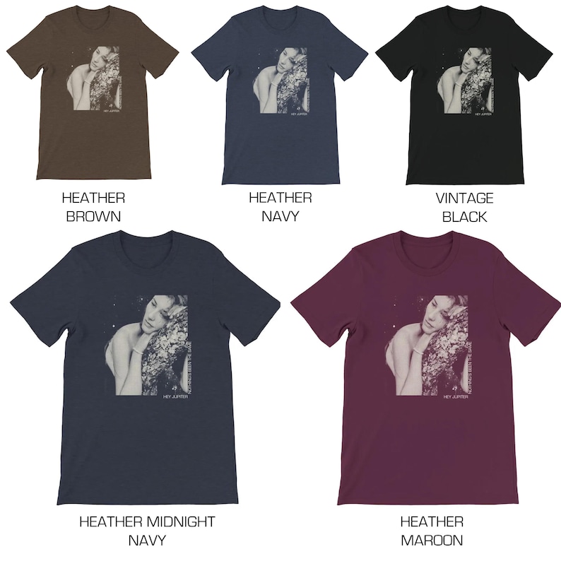 May include: Five t-shirts in different colors featuring a black and white image of a woman with her head resting on a tree branch. The image is printed on the front of the shirts. The colors of the shirts are heather brown, heather navy, vintage black, heather midnight navy, and heather maroon.