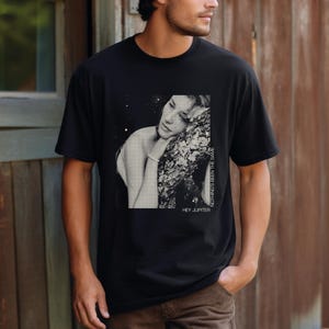 May include: Black t-shirt with a graphic print of a woman with her head resting on a tree branch. The text "HEY JUPITER" and "NOTHING'S BEEN THE SAME" are printed on the shirt.