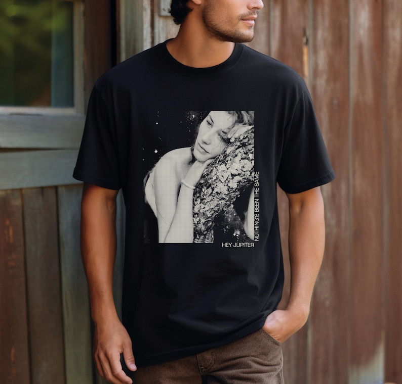 May include: Black t-shirt with a graphic print of a woman with her head resting on a tree branch. The text "HEY JUPITER" and "NOTHING'S BEEN THE SAME" are printed on the shirt.