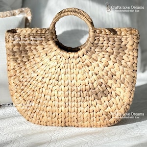 A woven straw handbag with a round handle, displayed on a white surface.